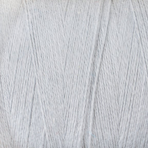 Close-up view of a large spool of light grey yarn, showing the texture and tightly wound fibers. The Maurice Brassard 8/2 Cottolin Organic Yarn | Tube highlights the soft and smooth appearance of the cotton-linen blend, perfect for knitting or crochet projects.