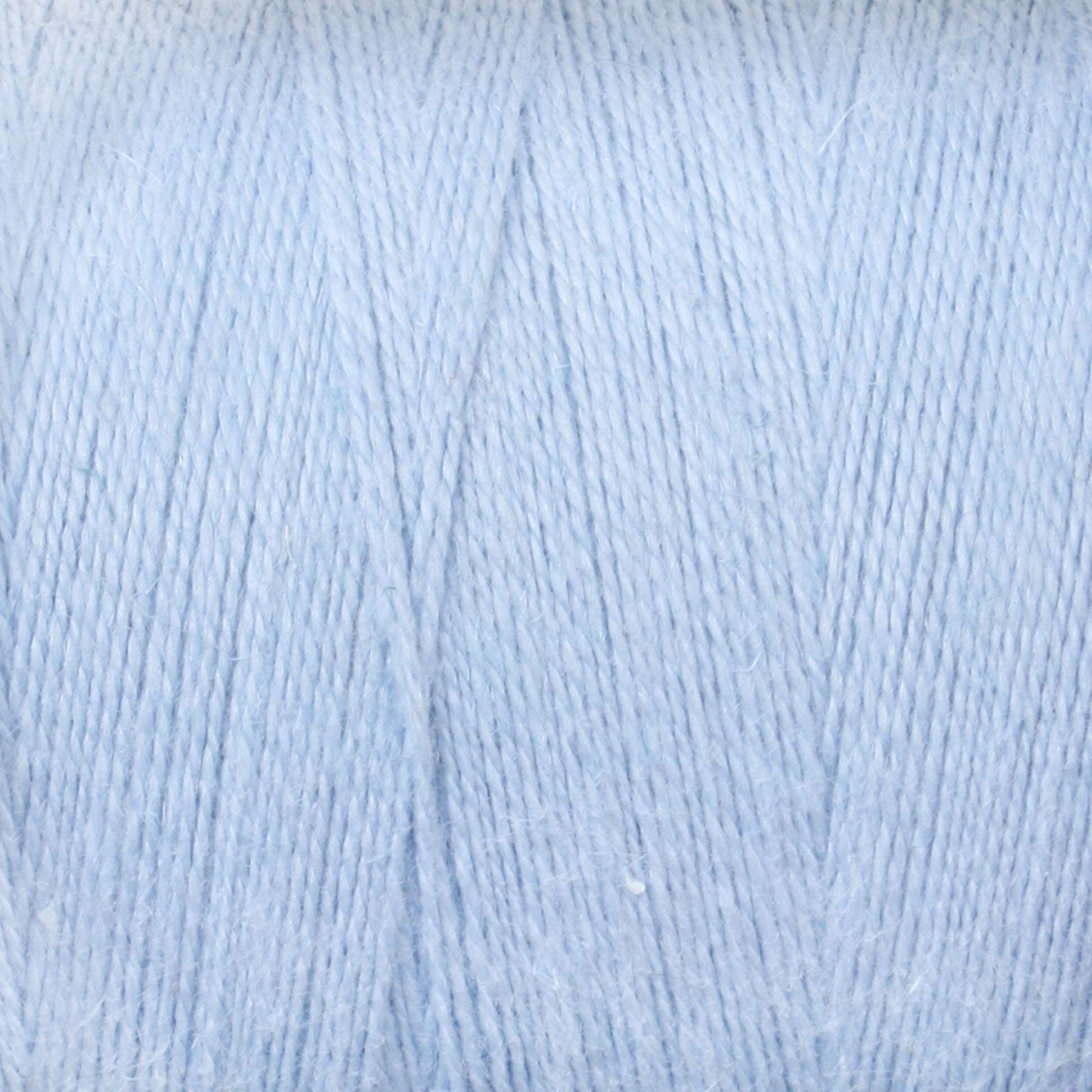 A close-up view of light blue yarn, highlighting the intricate texture and soft fibers woven together. The yarn appears smooth and tightly wound, reminiscent of the high quality found in Maurice Brassard's 8/2 Cottolin Organic Yarn | Tube. Ideal for knitting or crocheting projects.