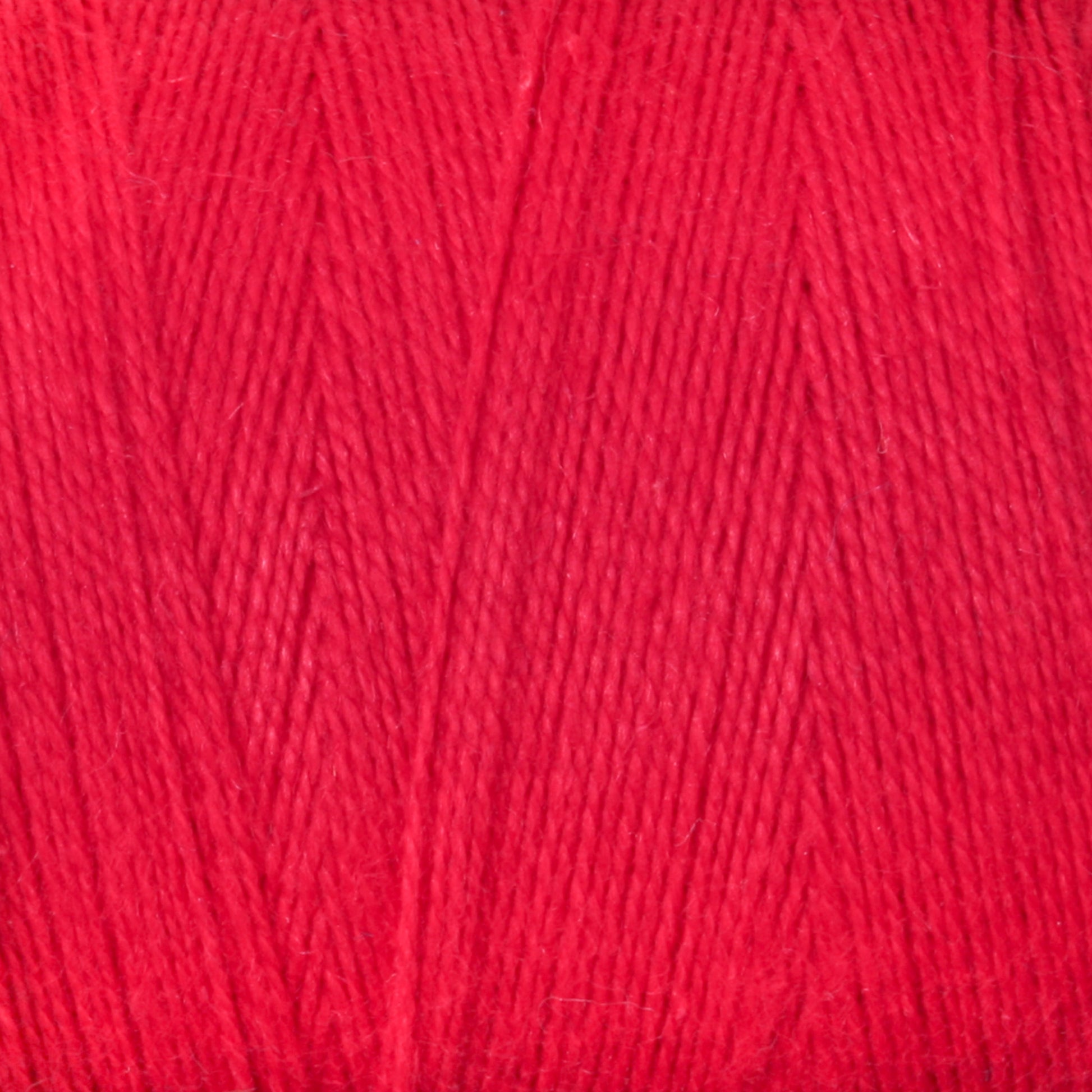 Close-up image of the 8/2 Cottolin Organic Yarn by Maurice Brassard, showcasing the bright red color and the texture of tightly wound fibers. This yarn, reminiscent of those found in a four shaft loom project, appears soft and suitable for knitting or crocheting projects.