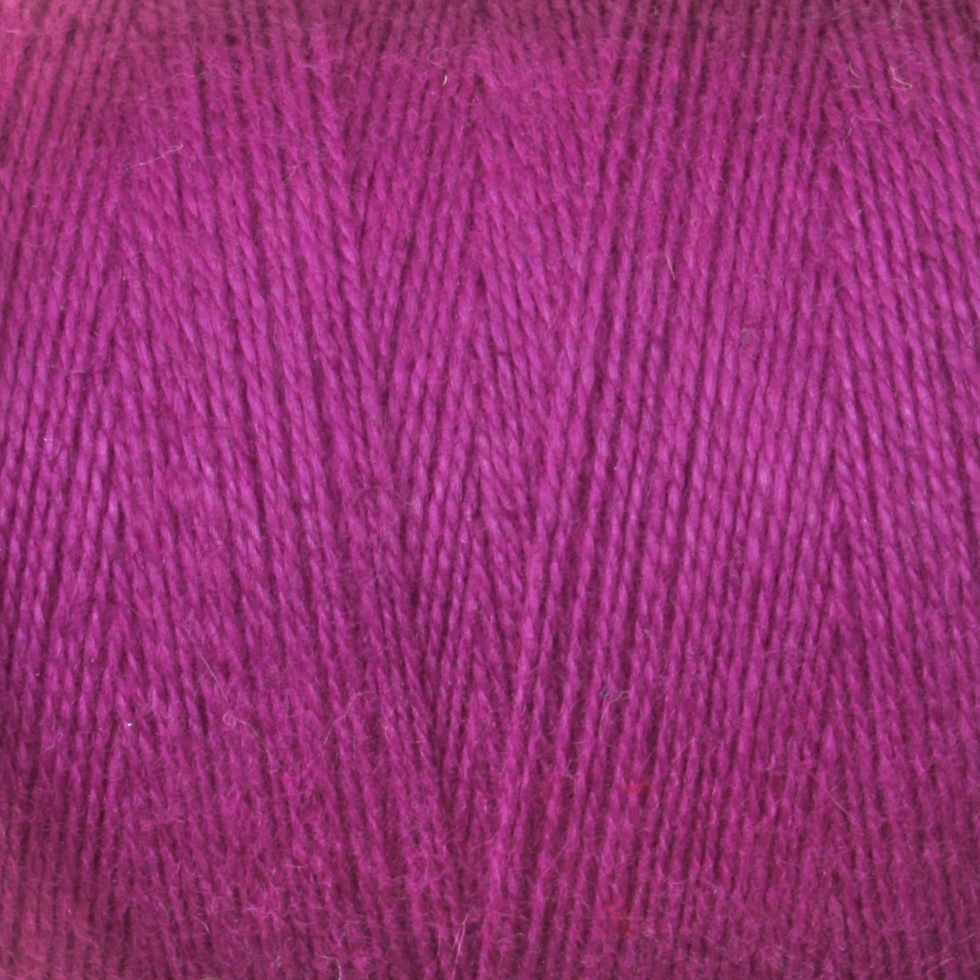 A close-up image of a tightly wound ball of magenta-colored 8/2 Cottolin Organic Yarn from Maurice Brassard. The texture is detailed, showing the individual fibers and the even, consistent twist of the threads—a perfect addition to a Cottolin Tea Towel Kit for those working on a four shaft loom.