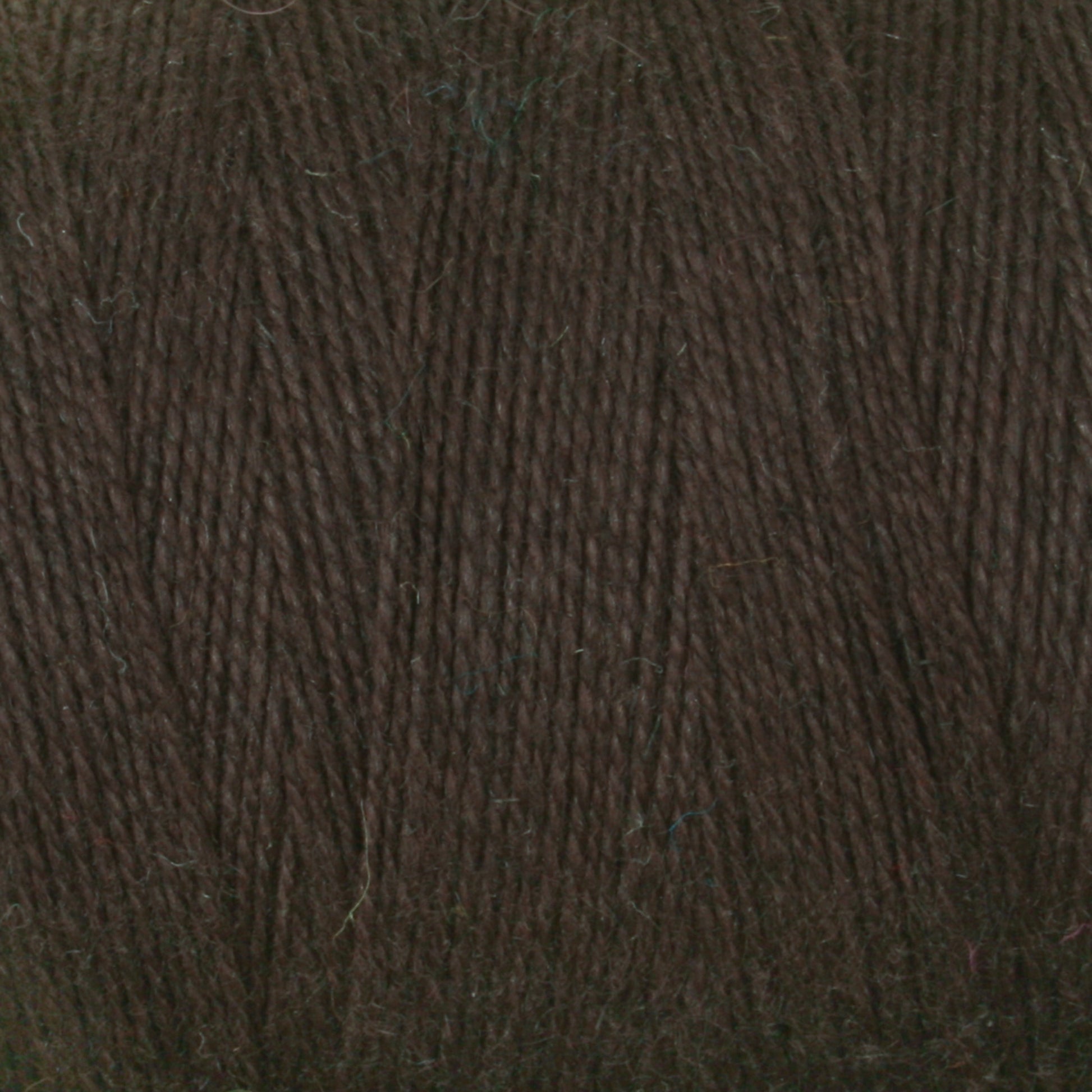 Close-up of a ball of Maurice Brassard's 8/2 Cottolin Organic Yarn in dark brown, showcasing its texture and tightly spun fibers, reminiscent of a cotton linen blend. The yarn appears soft and perfect for knitting or crocheting projects. The image highlights the uniform color and consistent strands of this high-quality yarn on the tube.