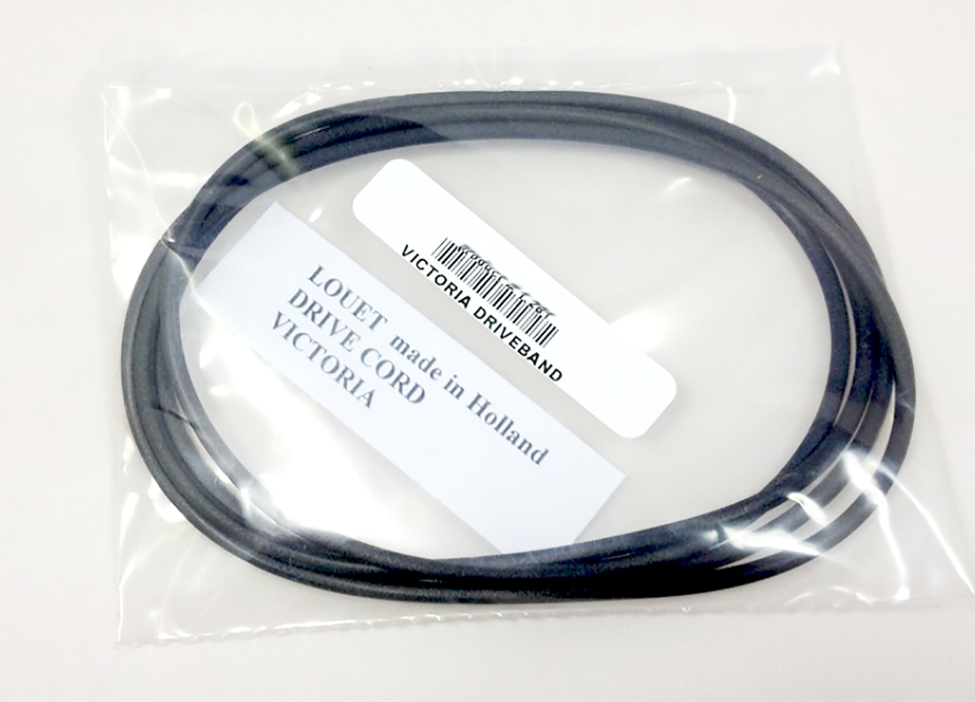 A coiled black drive cord, ideal for a Louët spinning wheel, is enclosed in a clear plastic bag. A white label inside the bag reads "LOUET Inc., made in Holland, DRIVE CORD, VICTORIA." Another attached label reads "VICTORIA DRIVEBAND.