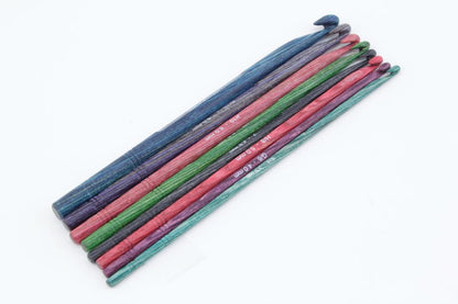 A set of colorful Knitter's Pride Symfonie Dreamz Wooden Crochet Hooks from Accessories Unlimited in various sizes is arranged in a neat row on a white background. The 8-hook crochet set features shades of blue, green, pink, and purple, each handcrafted from symfonie wood and marked with their respective sizes.