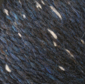 Close-up of dark blue Harrisville Designs Peace Fleece Yarn with flecks of white and lighter blue. The wool and mohair blend appears textured and soft, with a mix of colors that gives it a speckled, heathered look—perfect for worsted weight knitting projects.