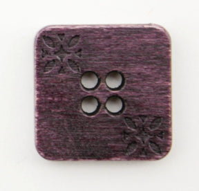 The Buttons Etc. Wood Square 3/4" Button is a finely crafted square wooden button with gently rounded corners. It features an etched floral design in two of its corners and has four central holes. The dark wood accentuates the intricate patterns, making it a delightful addition to any garment.