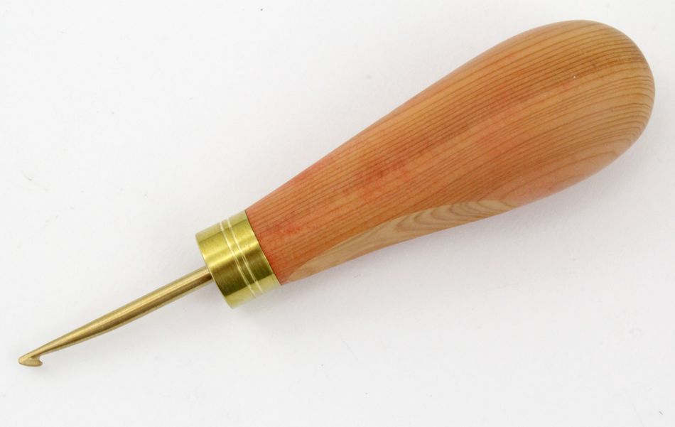 The Ergo Handle Hartman Hook by Dorr Fabrics Inc. is an ergonomic tool with a smooth, polished wooden handle that showcases the natural wood grain. Handcrafted in Ireland, this tool features an elegant brass and yew wood combination, a brass ferrule, and a small metal hook at the tip, making it ideal for crochet or needlework.