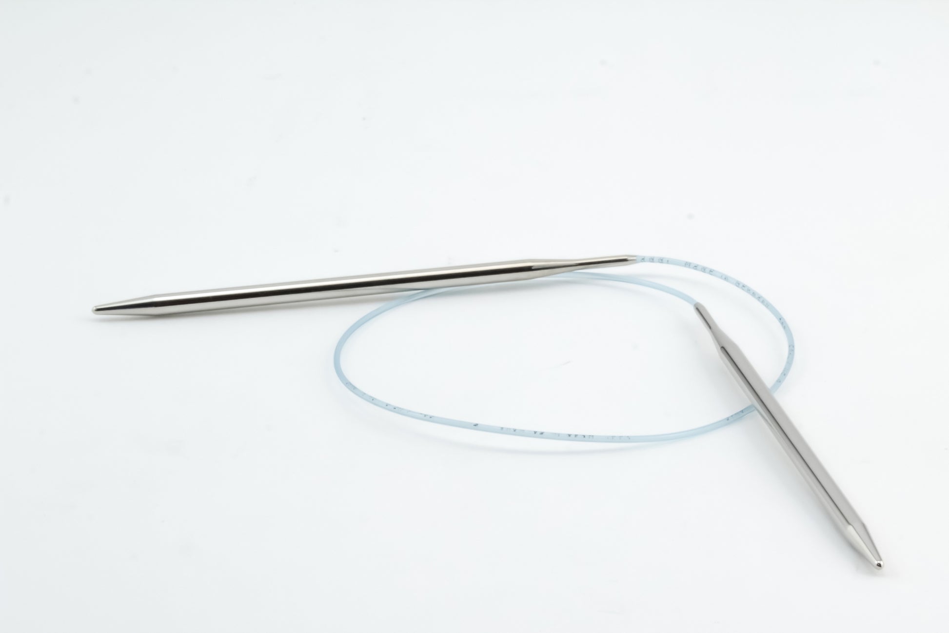 A set of Addi Turbo Circular Knitting Needles by Skacel features silver-colored tips connected by a flexible, translucent blue cable, ideal for crafting cuffs, collars, and doll clothes. Displayed on a plain white background.