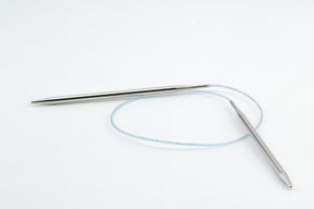 A set of Addi Turbo Circular Knitting Needles by Skacel features silver-colored tips connected by a flexible, translucent blue cable, ideal for crafting cuffs, collars, and doll clothes. Displayed on a plain white background.