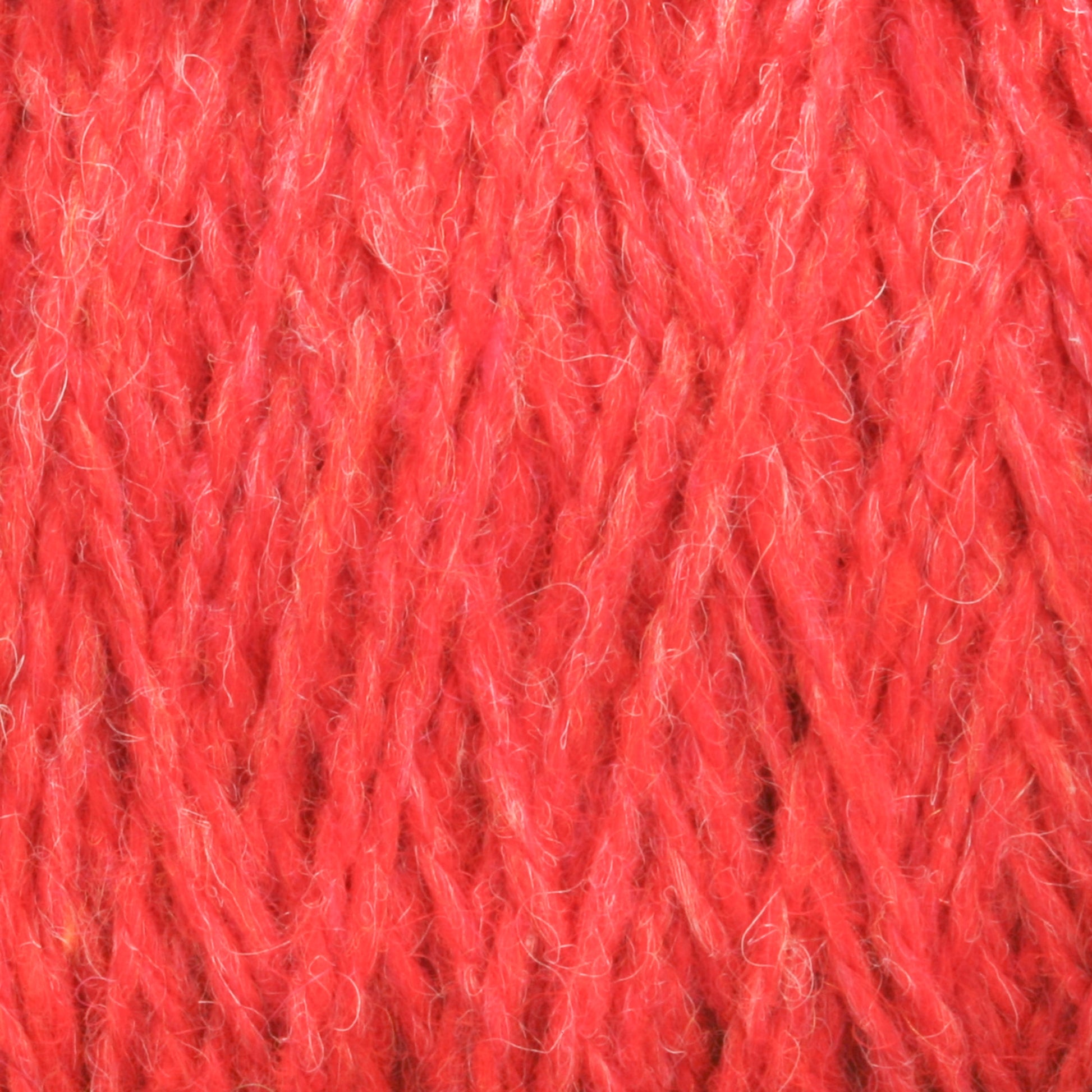 Close-up image of a vibrant red Harrisville Highland - Cones wool yarn from Harrisville Designs with interwoven fibers. The texture is thick, soft, and slightly fuzzy, showcasing the intricate pattern of threads enhanced by spinning oils.