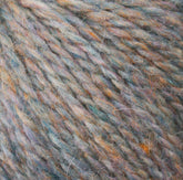 Close-up image of multicolored Peace Fleece Yarn by Harrisville Designs, highlighting grey, orange, blue, and purple threads with a soft and fuzzy texture. The wool and mohair blend fibers are intertwined, creating a thick and cozy appearance perfect for worsted weight knitting projects.