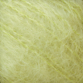 Close-up of soft, fluffy Victorian Brushed Mohair Yarn fibers in a light green shade, intertwined. The texture appears airy and delicate, with individual fibers visible and slightly fuzzy edges. This luxurious yarn from Caledonian Dye Works conveys a sense of warmth and coziness typically associated with lightweight, knit materials.