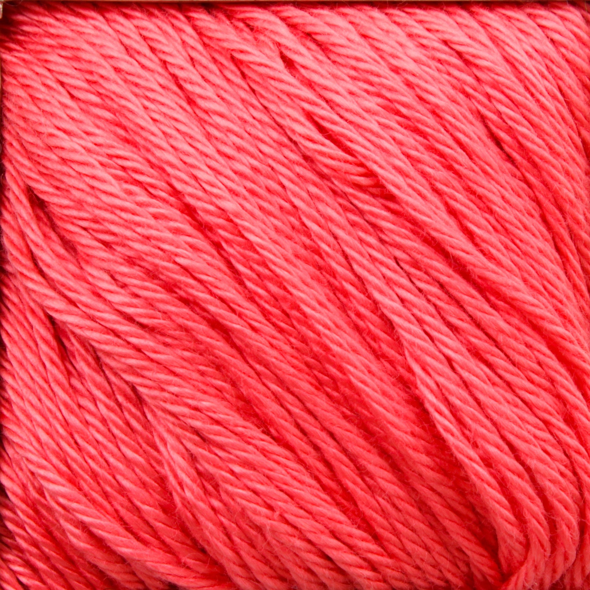 A close-up view of coral-colored Cascade Ultra Pima Cotton Yarn by Cascade Yarns, showcasing the texture and individual strands twisted together. The yarn has a smooth and slightly shiny appearance, with fibers neatly aligned and forming a consistent pattern throughout the image, highlighting its renowned soft hand.