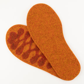 A pair of Adult's Thick Felt Slipper Soles w/Latex Grip from Joe's Toes in orange, featuring one overlapping the other, with the top sole displaying dark orange markings. Crafted from eco-friendly wool for ultimate comfort and support, they are set against a plain white background, reminiscent of a cozy felt slipper sole.