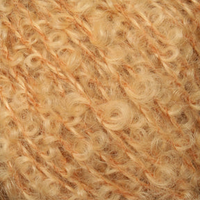 Close-up of a skein of soft, curly yarn from Caledonian Dye Works' Victorian Bouclé Mohair Yarn in a warm, light golden color. The yarn has a fuzzy, textured appearance with tightly wound curls and strands running through it.