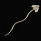 A Stick Shawl Pin by Bonnie Bishoff Designs, resembling a bee and made by local Maine artisan Bonnie Bishoff, displayed on a black background. This gold hairpin features detailed wings and a textured body, capturing the essence of a bee. The long, slender pin gracefully curves from the intricately designed top—making it an ideal unique gift.