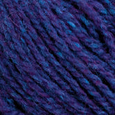 Close-up of unscoured yarn in purple and blue variegated hues. The fibers, thick and slightly fuzzy, are tightly twisted together, showcasing different shades of purple with hints of blue from Harrisville Highland - Cones by Harrisville Designs, creating a rich and textured pattern.