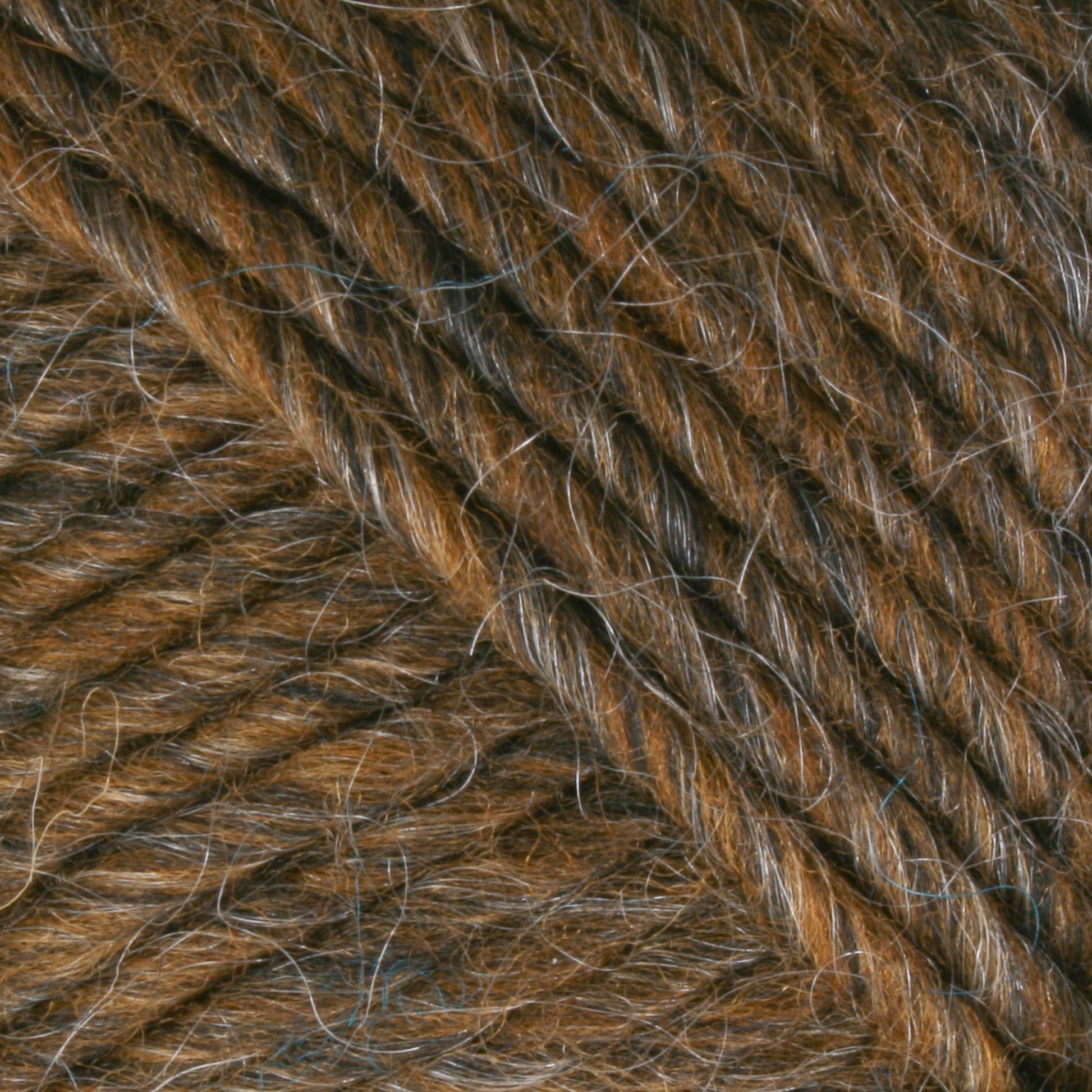 Close-up image of textured, Lamb's Pride Bulky Yarn in brown with subtle strands of gray interwoven. The fibers appear thick and soft, showcasing a rich and slightly variegated color palette. Ideal for knitters and crocheters, the image highlights the twist and intricate details perfect for creating woven blankets by Brown Sheep.