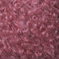 Close-up image of soft, pink curly fibers, resembling textured yarn or fur. The tight curls and vibrant color create a dense and fluffy appearance, reminiscent of Caledonian Dye Works' Victorian Bouclé Mohair Yarn.