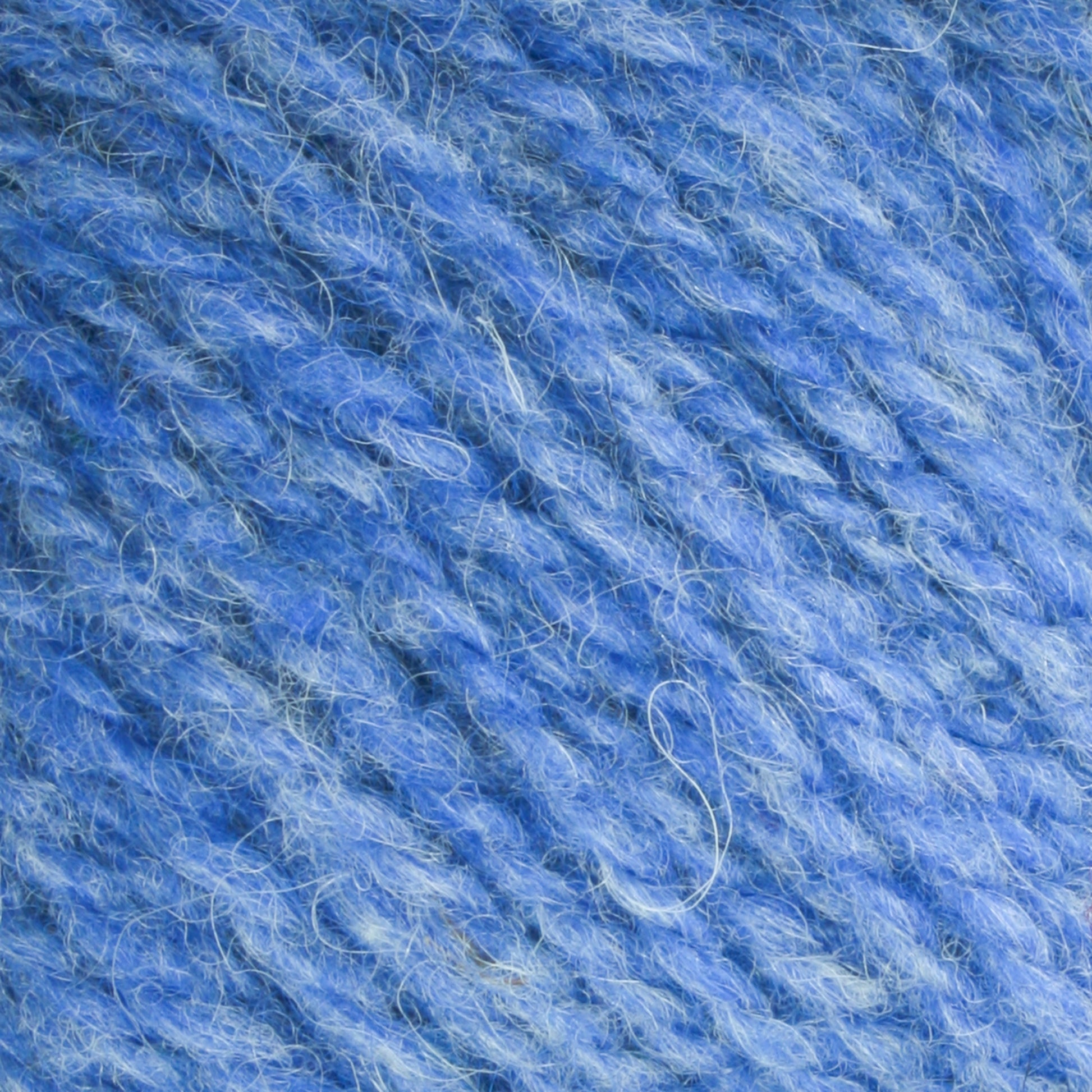 Close-up image of the soft blue Bartlettyarns Maine Wool Yarn. The fibers are loosely twisted, creating a textured and fluffy appearance. The yarn features various shades of blue, adding depth and a slightly heathered look. This worsted weight yarn from Bartlettyarns showcases beautiful heathered colors for added richness.