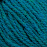 Close-up image of a ball of Harrisville Designs' Shetland Yarn - Unwashed Cones, featuring shades of blue and green. The yarn fibers are thick and softly twisted together, creating a textured appearance. Perfect for Fair Isle knitting designs, the colors blend seamlessly to give a beautifully variegated look.