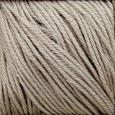 Close-up image of Cascade Ultra Pima Cotton Yarn by Cascade Yarns, tightly wound in a rectangular bundle. The light beige yarn features slightly textured individual fibers that are neatly aligned, showcasing the twisted strands' intricate pattern and soft appearance. Crafted from Peruvian Pima Cotton, it's ideal for knitting or crocheting projects.