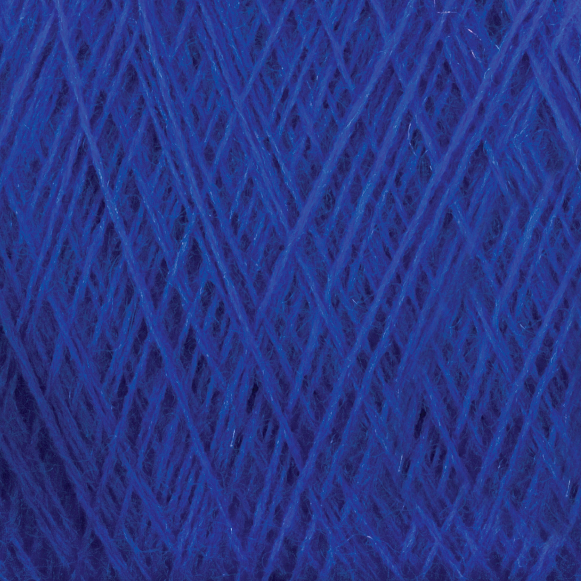 A close-up view of a tightly wound ball of Jagger Brothers, Inc.'s JaggerSpun Maine Line 3/8 Yarn | Large Cone, showcasing intricate layers and textures of the fibers and strands. The worsted spun yarns appear soft and boast a consistent shade of deep blue.