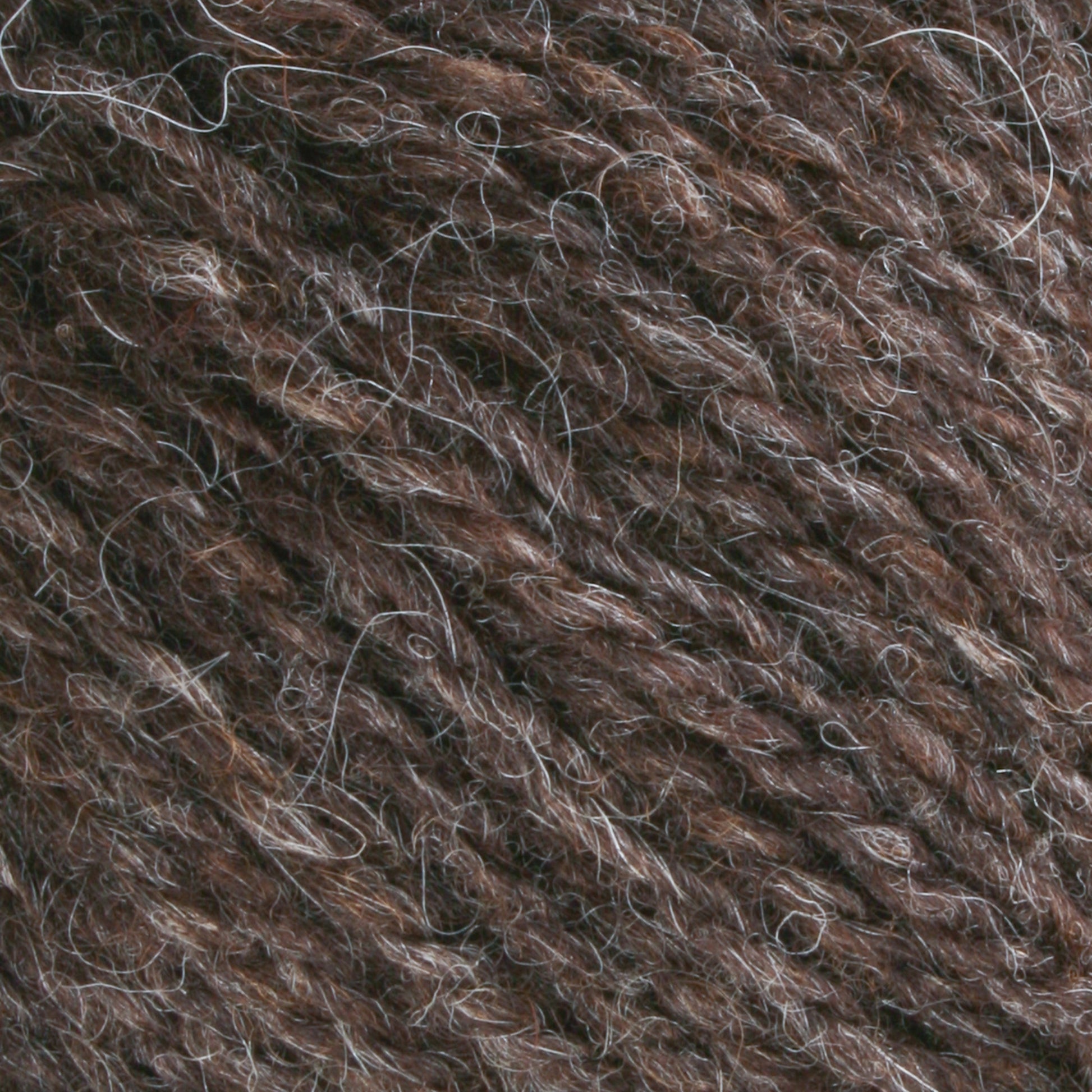 Close-up of Bartlettyarns Maine Wool Yarn, fibers loosely wound together, showcasing a textured and slightly coarse surface. The classic worsted weight yarn features a mix of dark and light, heathered colors that give it a rich, marbled appearance.