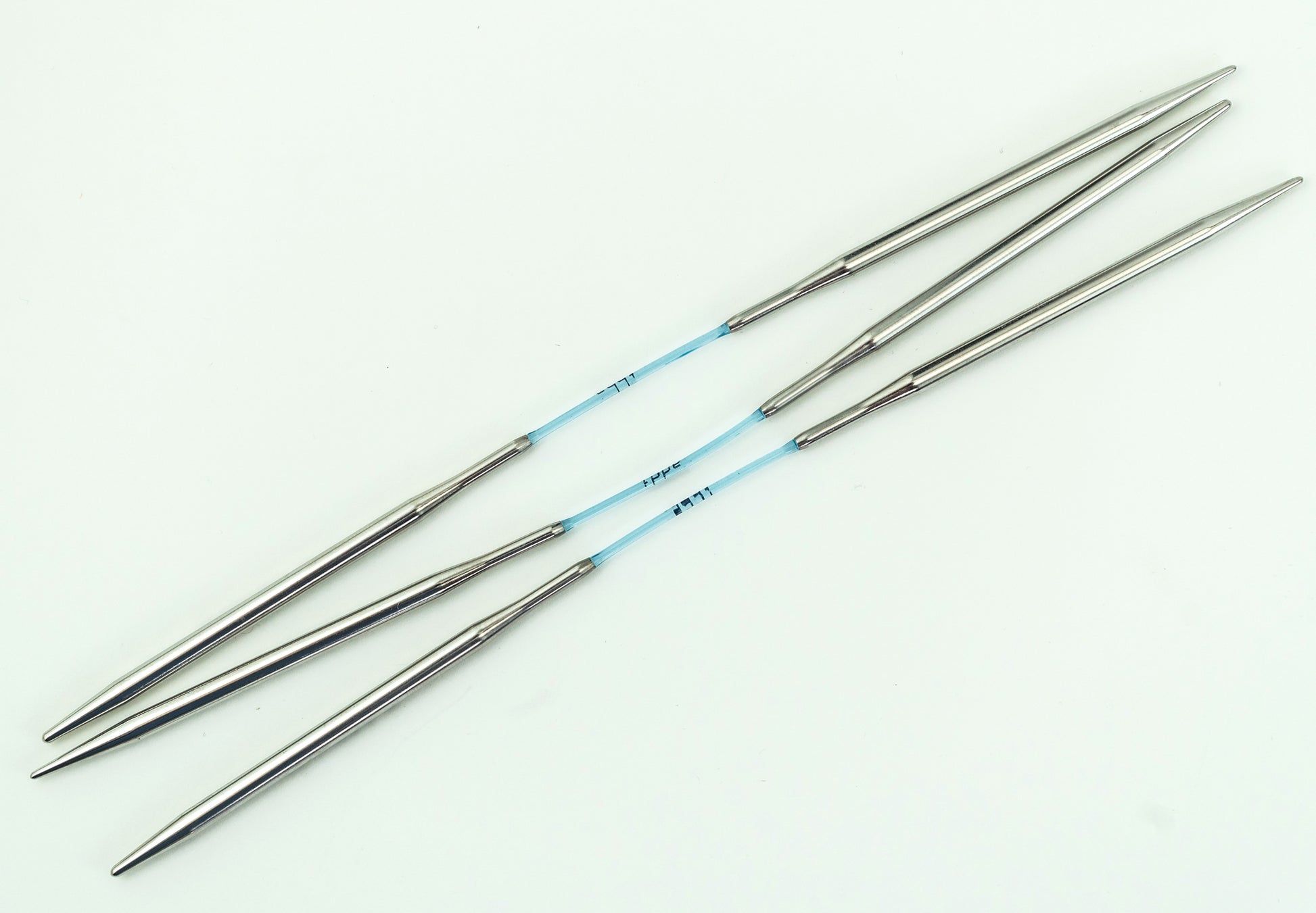 Two sets of Skacel Addi FlexiFlips Circular Needles, ideal for knitting socks, are connected by blue, flexible cables and arranged parallel to each other on a white background. These circular needles are smooth and taper to fine points.