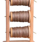 The Ashford Lazy Kate by Ashford Handicrafts Limited is a vertical wooden spool holder that comes with three spools of brown-tinted thread. It features two posts connected by three thin metal rods, each holding one spool, which are evenly spaced and securely mounted.