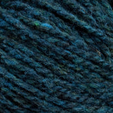 Close-up image of dark blue and green Harrisville Shetland Yarn - Unwashed Cones by Harrisville Designs, showcasing its textured, intertwined pattern with a mix of hues and soft, fibrous strands, perfect for creating lightweight blankets.