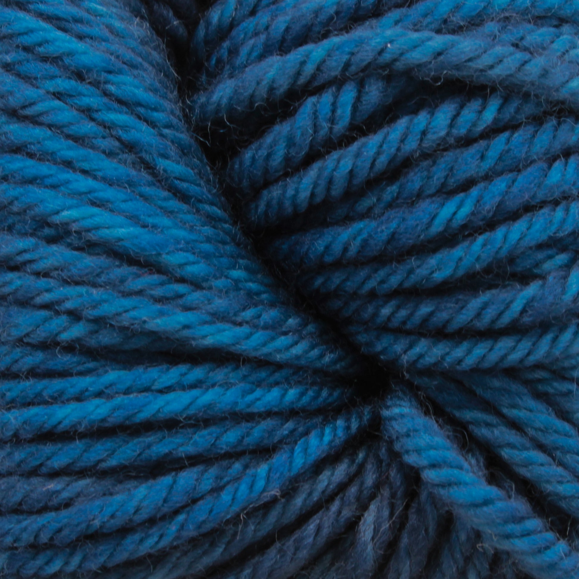 Close-up of a skein of Malabrigo Yarn's Rios, showcasing tightly wound strands with kettle-dyed colors ranging from dark navy to lighter turquoise. The texture appears soft and slightly fuzzy, perfect for your next superwash yarn project.