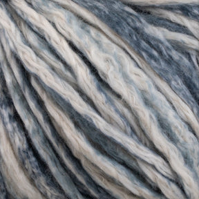 Close-up of a bundle of thick, multicolored Cumulus Cotton by Juniper Moon Farm yarn with strands of white, light blue, and dark blue fibers intertwined, creating a textured pattern. This soft yarn features durable chainette construction by Knitting Fever / Euro Yarns, making it perfect for knitting or crocheting projects and weightless accessories.