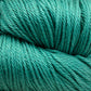 Close-up image of a large skein of Cascade Ultra Pima Cotton Yarn in turquoise, showcasing its soft and slightly shiny texture. The tightly wound fibers suggest the Peruvian Pima cotton from Cascade Yarns is smooth and suitable for knitting or crocheting with a soft hand.