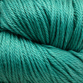 Close-up image of a large skein of Cascade Ultra Pima Cotton Yarn in turquoise, showcasing its soft and slightly shiny texture. The tightly wound fibers suggest the Peruvian Pima cotton from Cascade Yarns is smooth and suitable for knitting or crocheting with a soft hand.