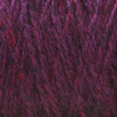 A close-up shot of purple and red variegated Harrisville Highland - Cones yarn from Harrisville Designs showcases its soft, fuzzy texture with interwoven strands creating a rich, multi-tonal appearance. Traces of spinning oils are still visible.