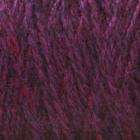 A close-up shot of purple and red variegated Harrisville Highland - Cones yarn from Harrisville Designs showcases its soft, fuzzy texture with interwoven strands creating a rich, multi-tonal appearance. Traces of spinning oils are still visible.