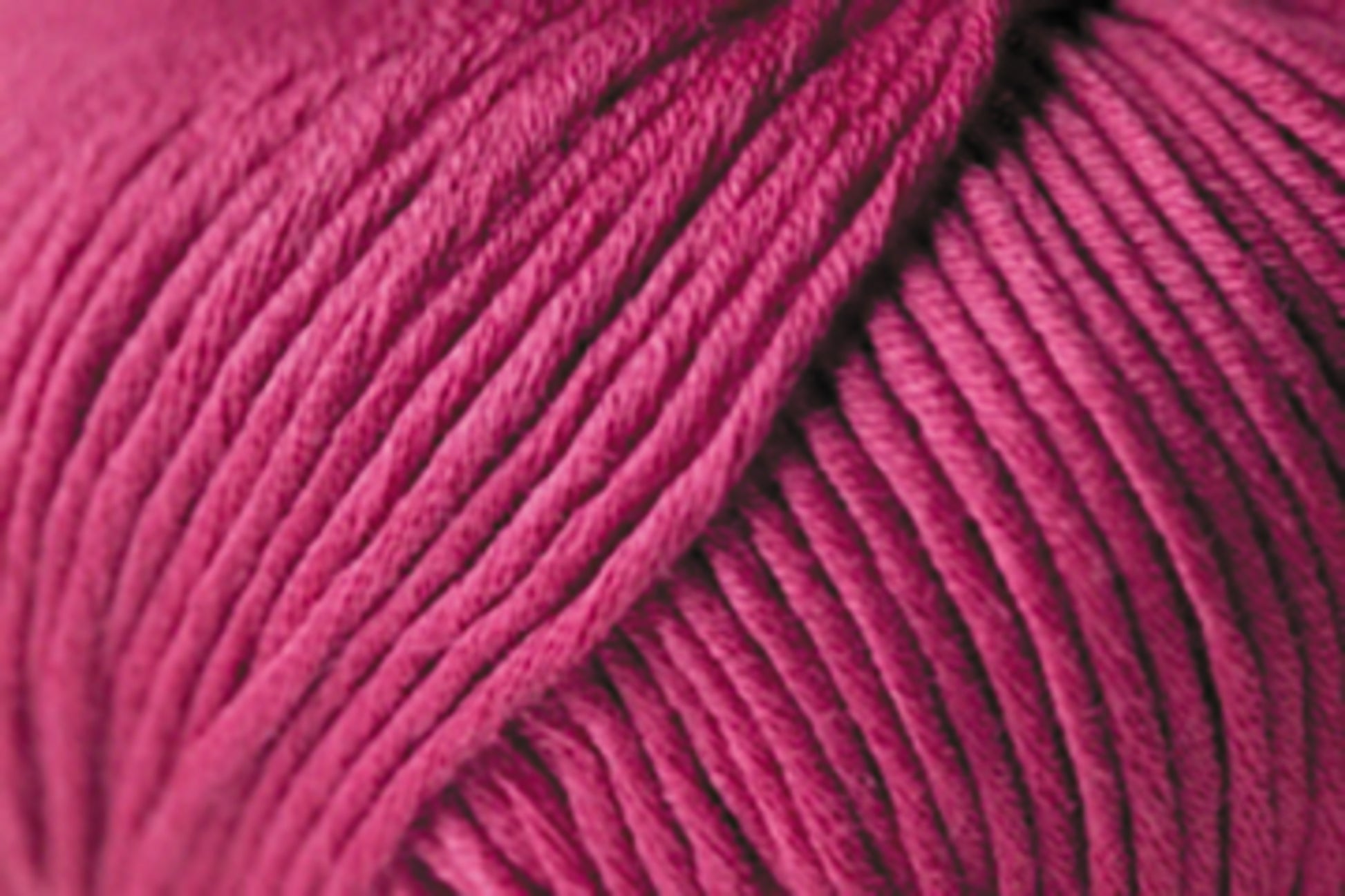 Close-up image of a ball of Jo Sharp Soho Summer DK Cotton by Kingfisher Yarn & Fibre in a rich magenta color. The yarn appears thick with individual strands tightly wound together, showcasing its texture and smoothness. The image highlights the lightweight cotton's detail and vibrant hue, perfect for summer knitting projects.