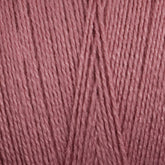 Close-up view of Maurice Brassard's 8/2 Bamboo Yarn | Tube in a soft, muted pink color. The strands are tightly wound together, showcasing the yarn's fibrous detail and slightly glossy sheen. This eco-friendly bamboo yarn offers antibacterial properties while maintaining its delicate charm.