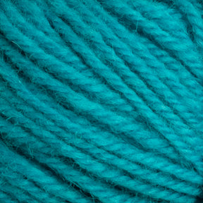 Close-up view of a ball of Halcyon Deco Rug Wool by Caledonian Dye Works, showcasing the detailed texture and fibers. The tightly wound yarn, made from 100% wool, appears soft and slightly fuzzy with a vibrant and consistent teal color throughout.