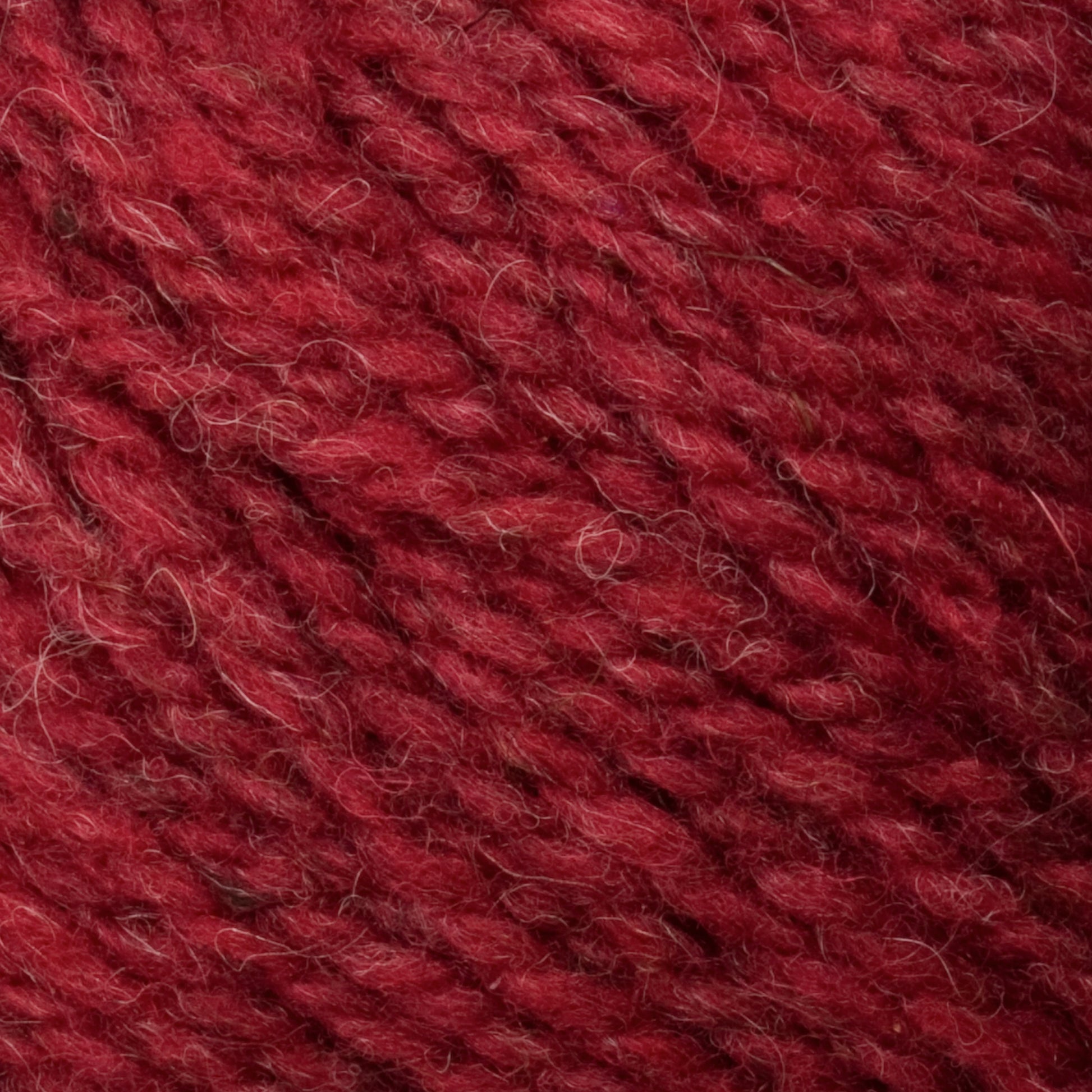 Close-up view of red Bartlettyarns Maine Wool Yarn from Bartlettyarns showing a soft, slightly textured surface with visible strands tightly woven together. The yarn has subtle variations in heathered colors, creating a rich and warm overall color.