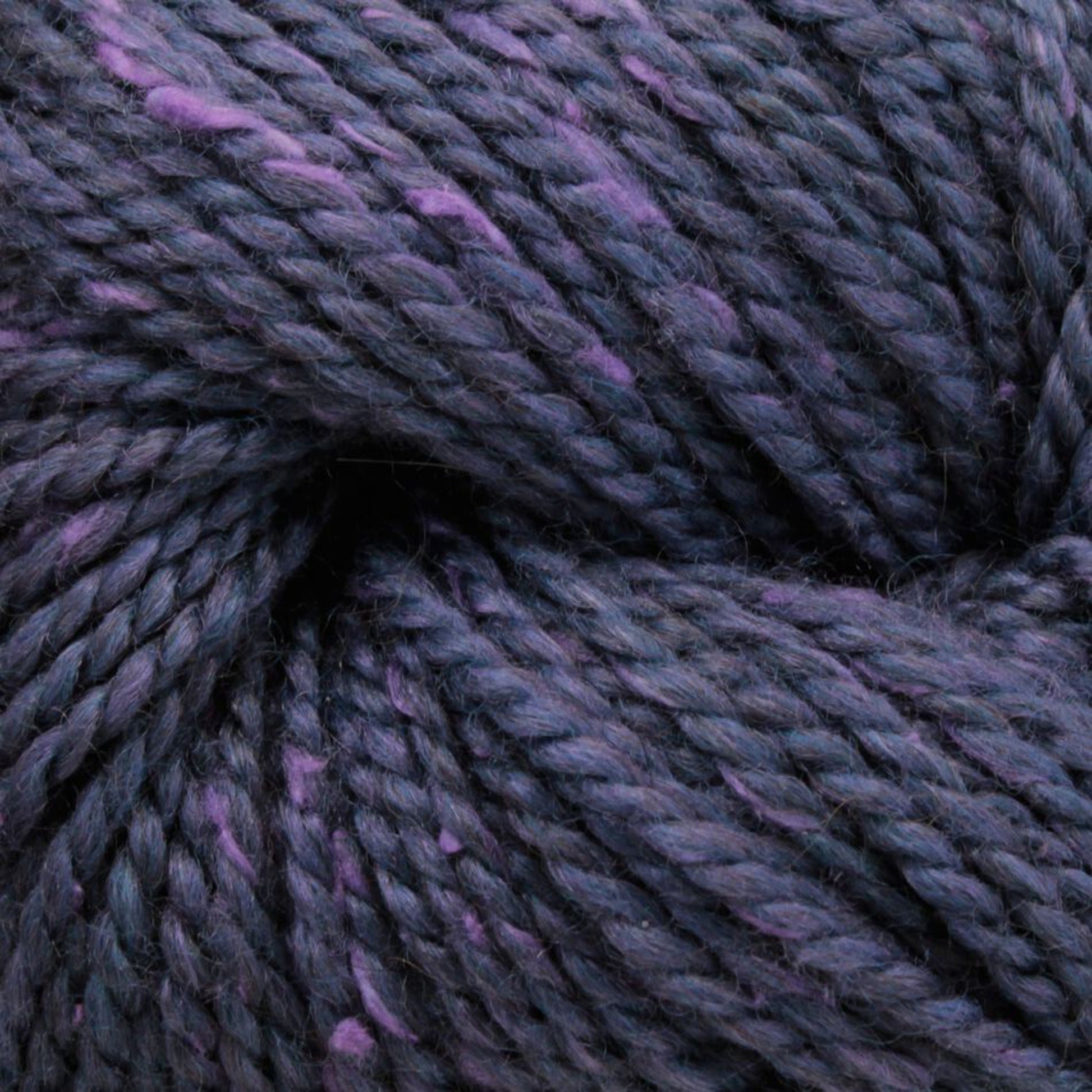 Close-up of a twisted skein of Acadia by The Fiber Company yarn from The Fibre Co. (UK) Ltd, showcasing strands of dark purple interspersed with lighter purple and dark blue hues. The texture appears soft and slightly fuzzy, embodying a subtle tweed effect that hints at natural scenic beauty.