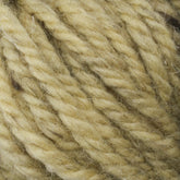 Close-up of a ball of thick, twisted Halcyon Yarn Classic Rug Wool from Caledonian Dye Works, featuring an uneven texture with tightly intertwined fibers. The yarn showcases variations of light beige color, giving it a rough and woolly appearance, ideal for knitting or crafting projects. Perfect for rug weavers seeking the durability of Classic Rug Wool.