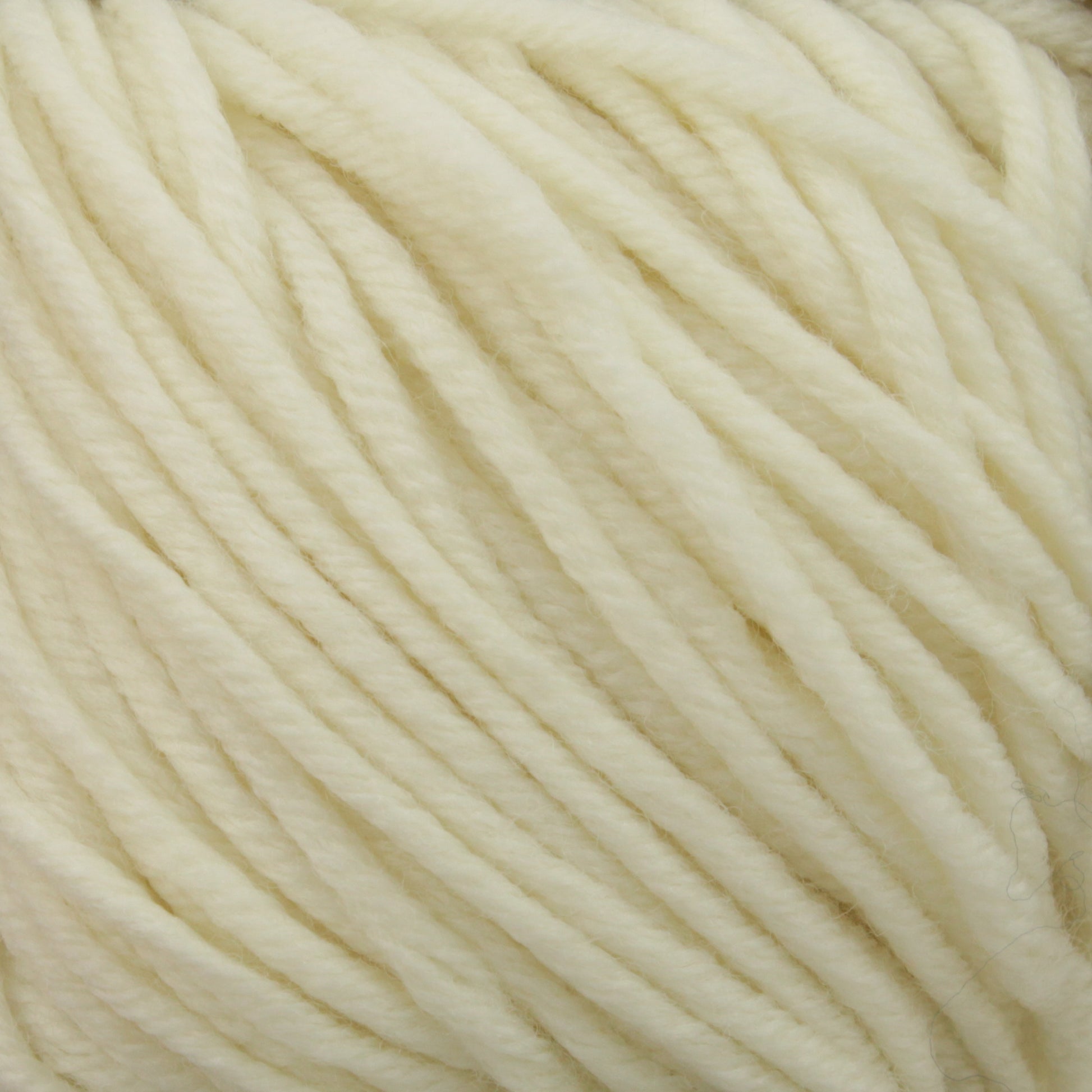 A close-up view of soft, cream-colored yarn strands tightly wound together. The yarn appears thick and plush, suggesting it may be used for knitting or crochet projects. Made from Plymouth Select Worsted Merino Superwash by Plymouth Yarn Co., the texture is smooth with a slightly fuzzy surface typical of superwash fibers, promising excellent stitch definition.