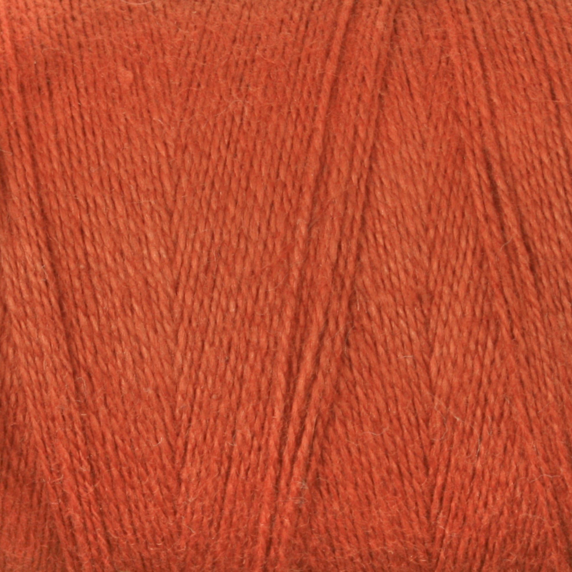 Close-up of red yarn. The image showcases the fine texture and even strands of yarn, reminiscent of the quality you'd find in Maurice Brassard's 8/2 Cottolin Organic Yarn | Tube, creating a warm and saturated appearance.