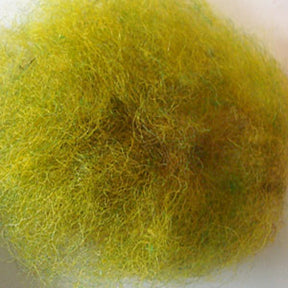 A close-up image of a fuzzy, yellow-greenish ball of lint with visible fine fibers and an irregular, cloud-like shape reminiscent of Harrisville Dyed & Carded Wool Fiber by Harrisville Designs. The texture appears soft and slightly matted, set against a plain, light-colored background.