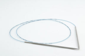 The Addi Turbo Circular Knitting Needles by Skacel feature an angled, metallic design with a long, flexible, translucent tube. The tube, reminiscent of coiled short circular needles used in knitting, is transparent and marked with blue indicators. Both the needles and the tubing are displayed against a plain white background.