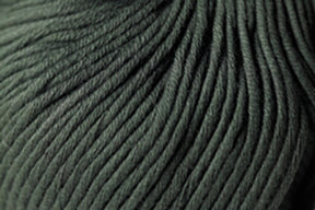 Close-up image of a ball of dark green Jo Sharp Soho Summer DK Cotton by Kingfisher Yarn & Fibre, showcasing the texture and tightly wound strands. The individual fibers are visible, highlighting the soft and dense appearance of this lightweight cotton yarn.