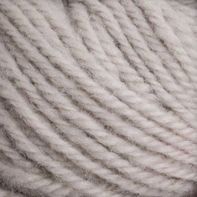 Close-up image of light grey, twisted Halcyon Deco Rug Wool made from 100% wool by Caledonian Dye Works, showcasing its soft and fuzzy texture. The tightly wound strands create a coiled pattern, emphasizing the yarn's thickness and fibrous quality, perfect for creating a versatile deco rug.