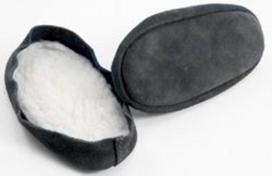 A pair of Bryson Distributing, Inc.'s Suede Leather and Fleece Soles slippers, one laying face up showcasing its fuzzy white fleece lining, and the other laying face down displaying its smooth suede sole.