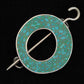 The Single Circle Shawl Pin by Bonnie Bishoff Designs is a circular brooch featuring a mosaic pattern of turquoise polymer clay tiles set in silver, with an open center and a hook-like clasp accompanied by an attached pin for fastening. The background is black. This stunning piece is brought to you by Bonnie Bishoff.